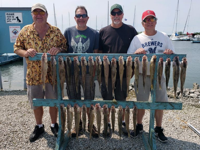 4 men showing off their catch after returning on charter